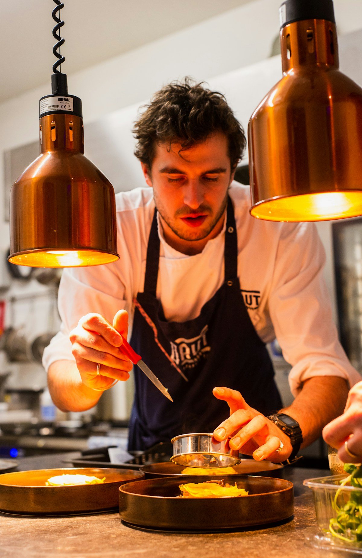 Chef plating a dish under the pass